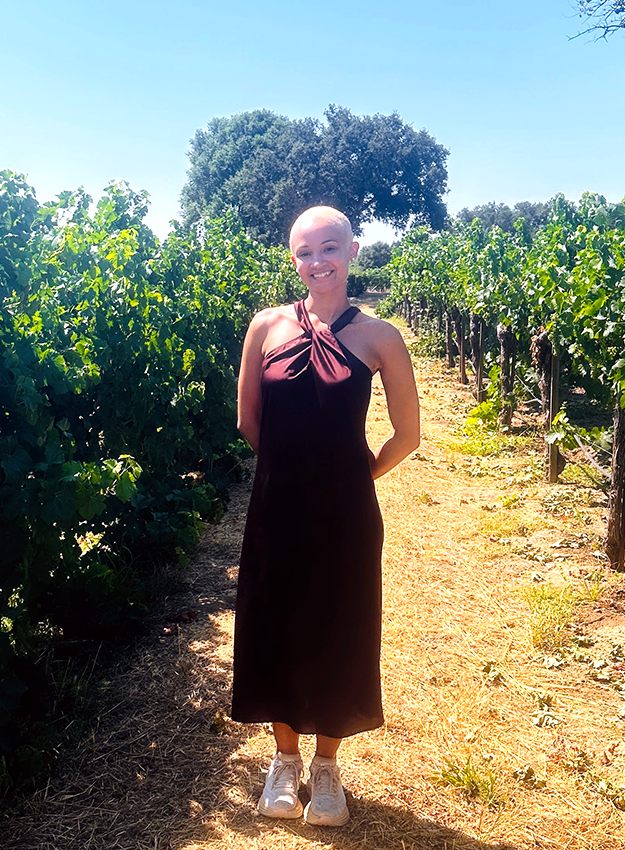 Woman standing between vineyard rows